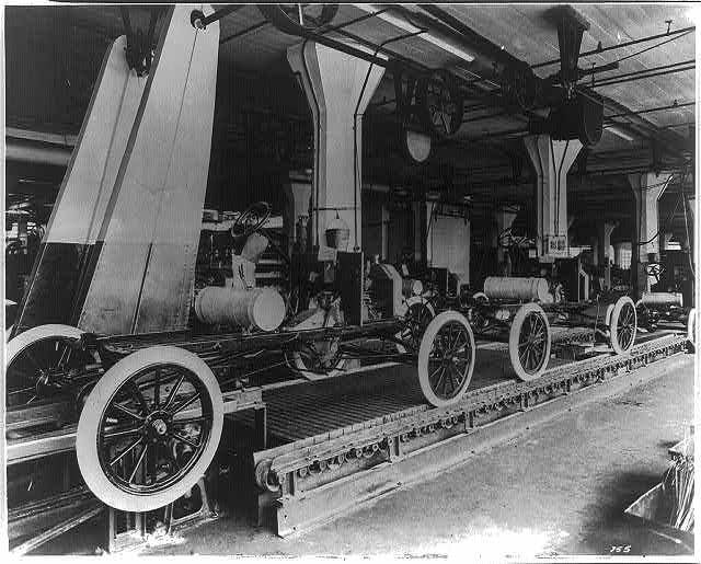 Ford assembly line circa 1913 — workers positioned between machines in a structured production flow